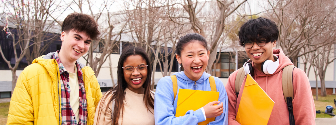 Confident multiracial group of students holding books and smiling at camera, campus university on background, learning and education concept. Smiling happy people having fun together. International